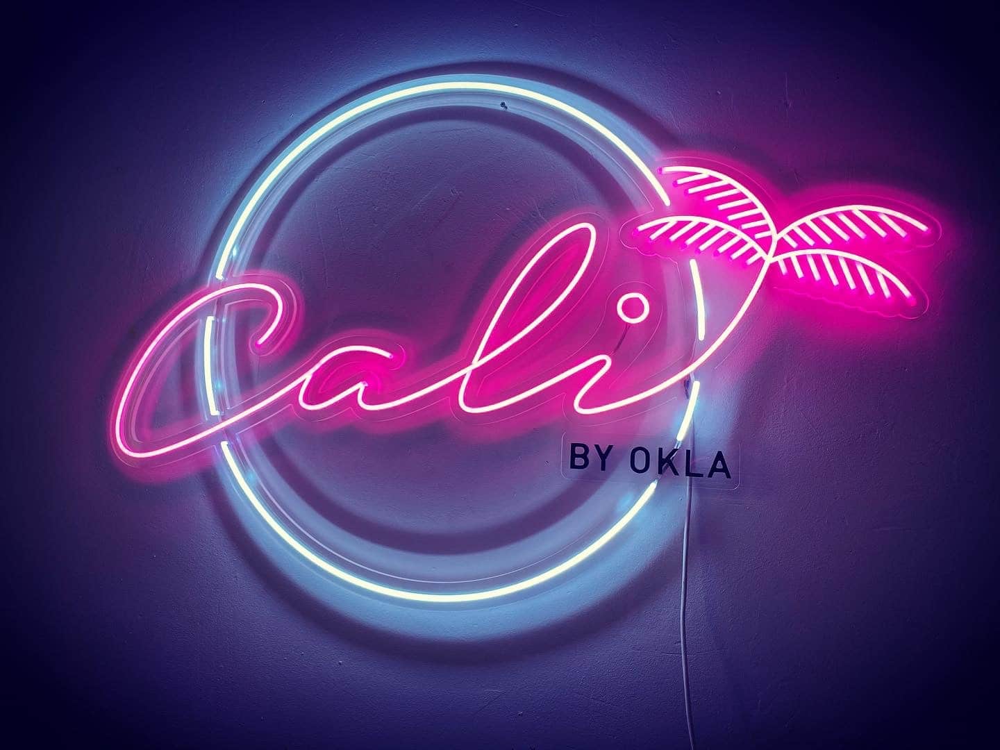 Néon mural rose et bleu « Cali by Okla » avec palmier et cercle lumineux