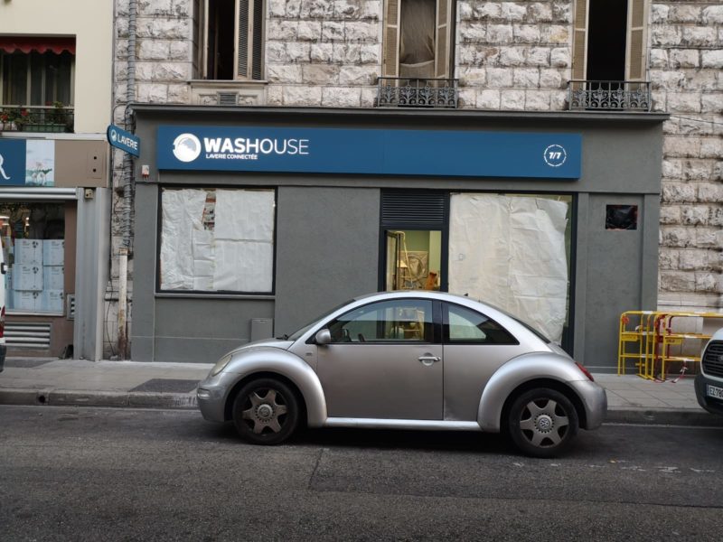 Façade de la laverie Washouse avec enseigne lumineuse et drapeau « Laverie »