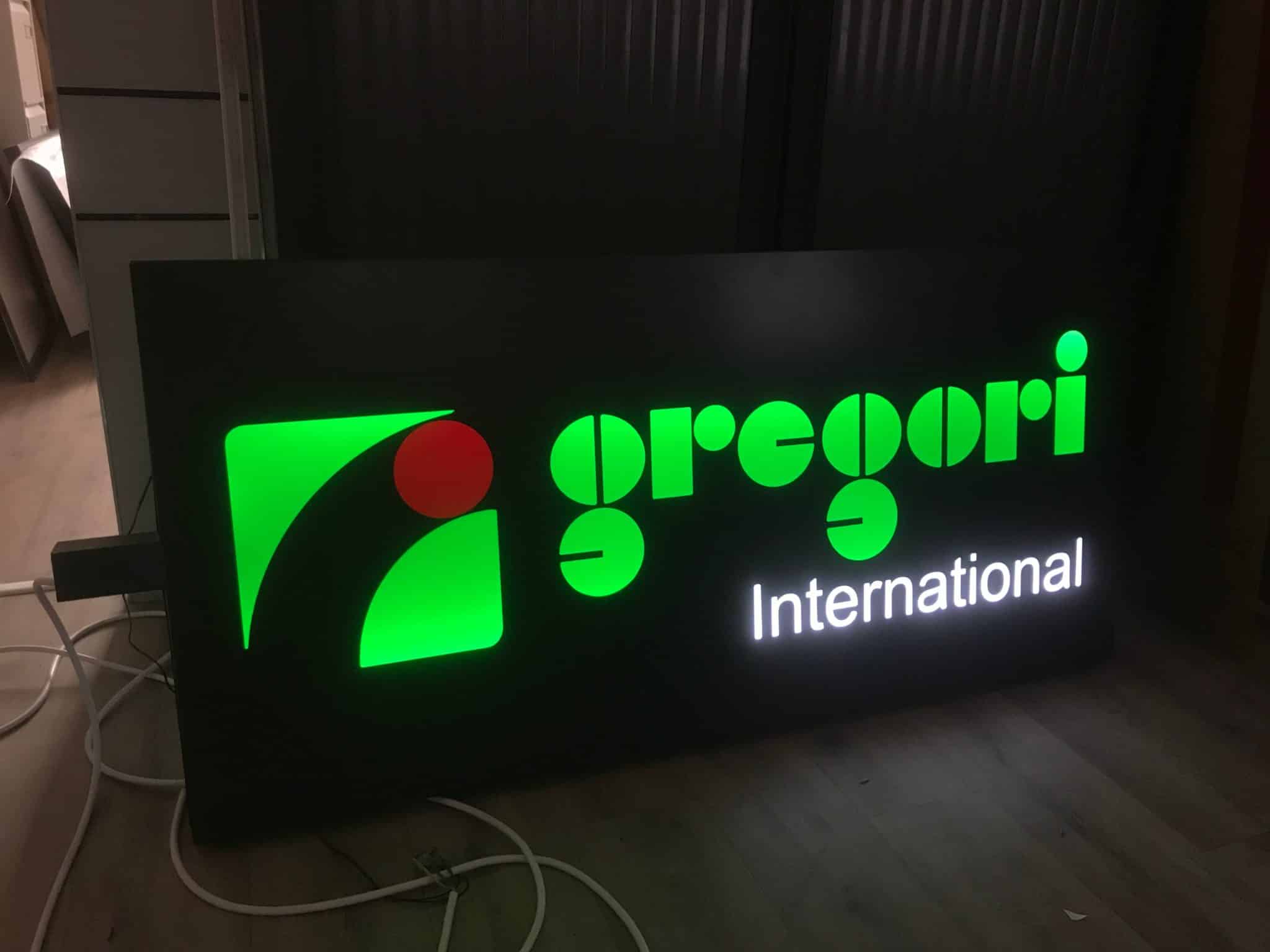 Enseigne lumineuse Gregori International avec logo vert rétroéclairé sur fond noir